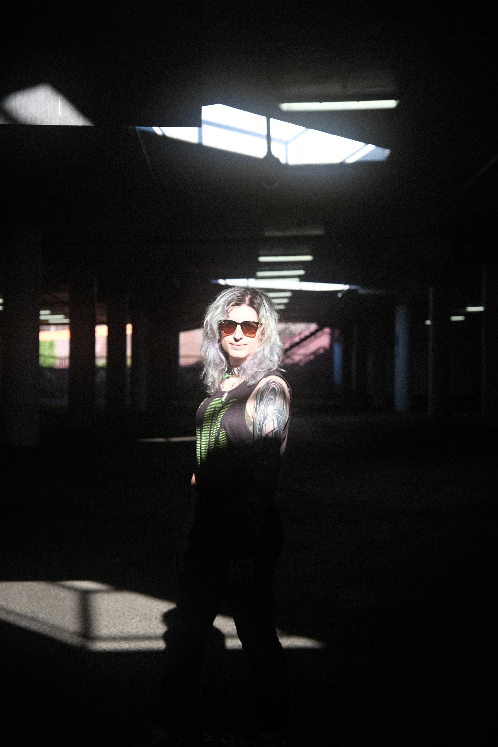 raven standing in a parking structure with a sunbeam on her face