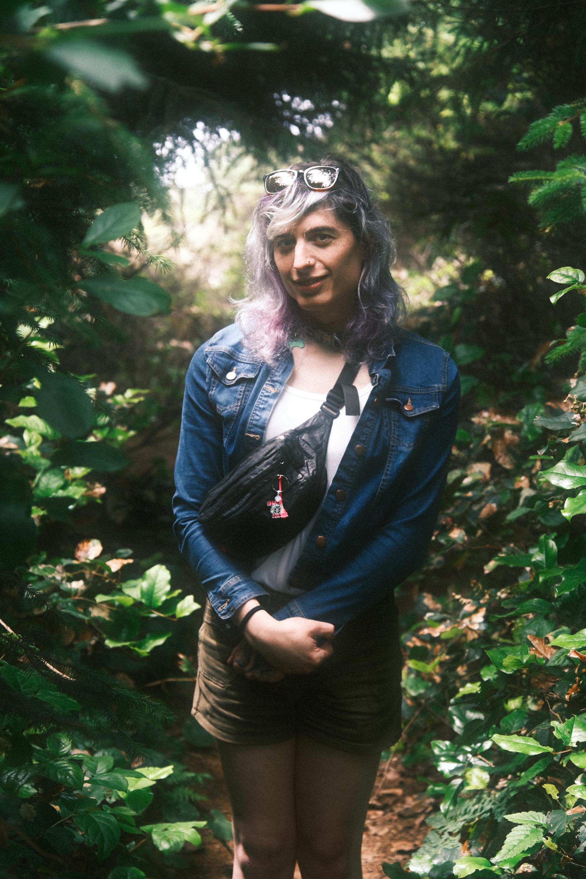 raven among some foliage facing the camera wearing her jean jacket (currently with another woman)