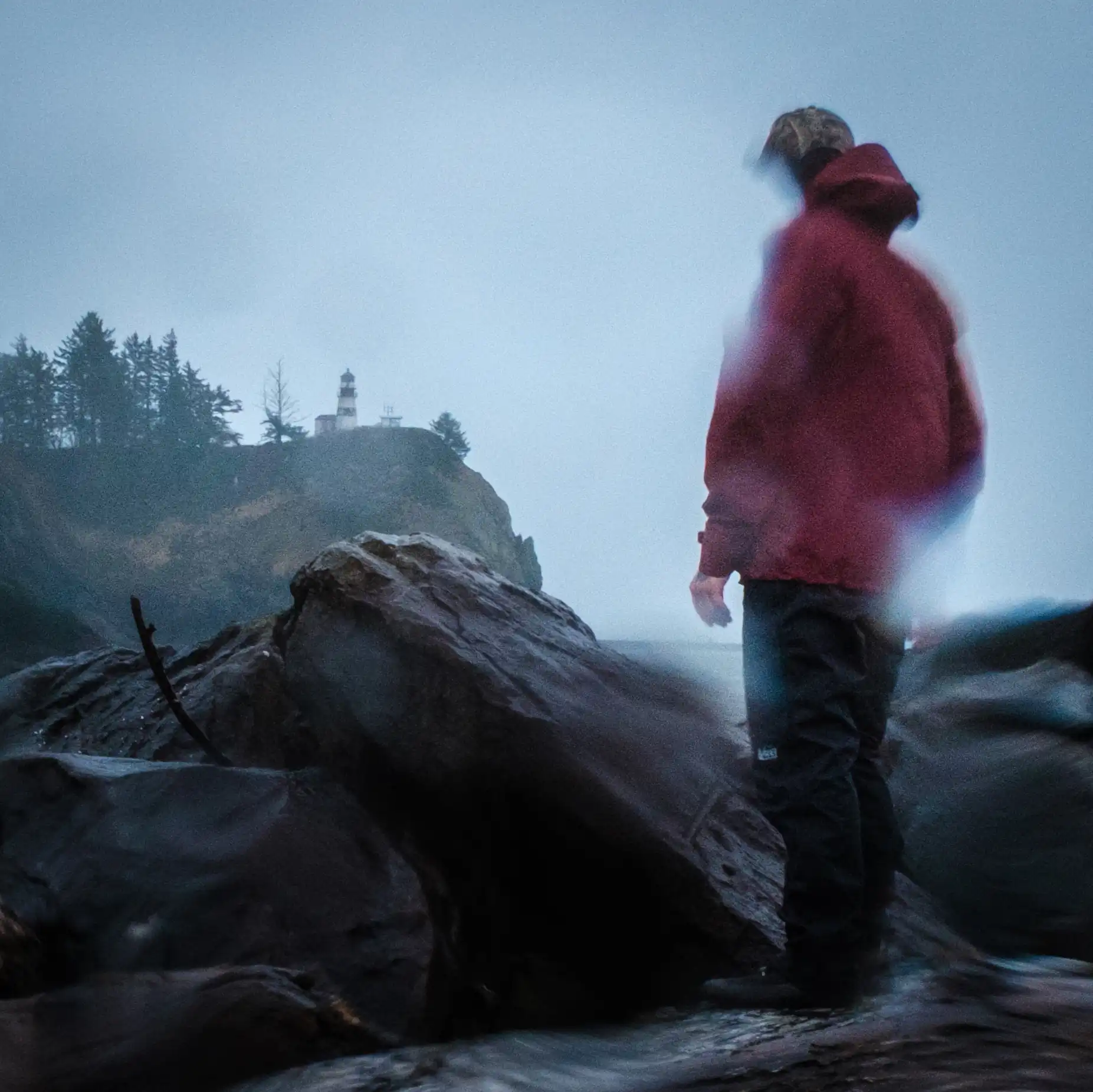 raven stands with her back to the camera on an self-timed photo at Cape Dissapointment in Washington