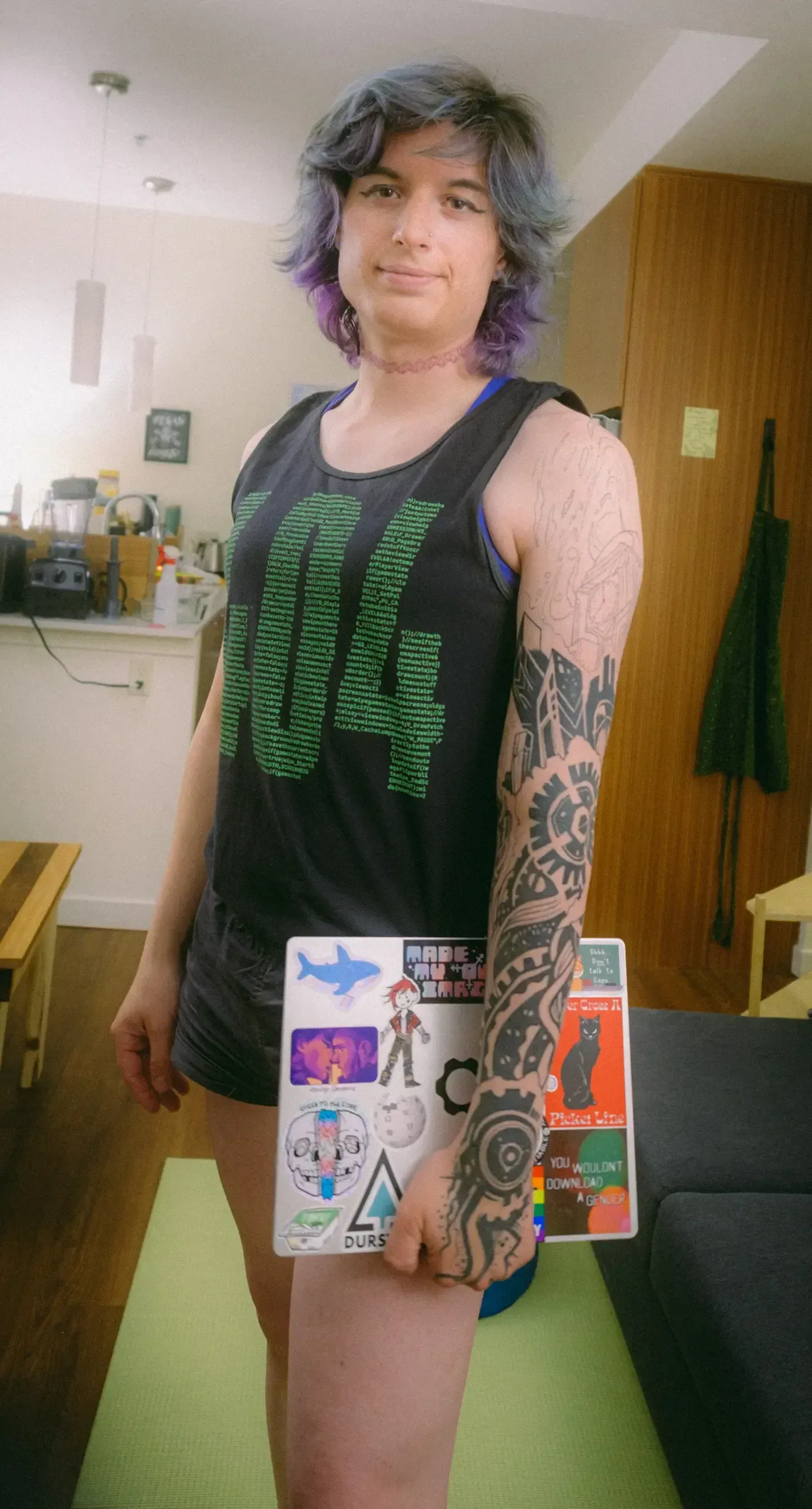 author looking at the camera holding a laptop wearing a sleeveless shirt that says 404 on it