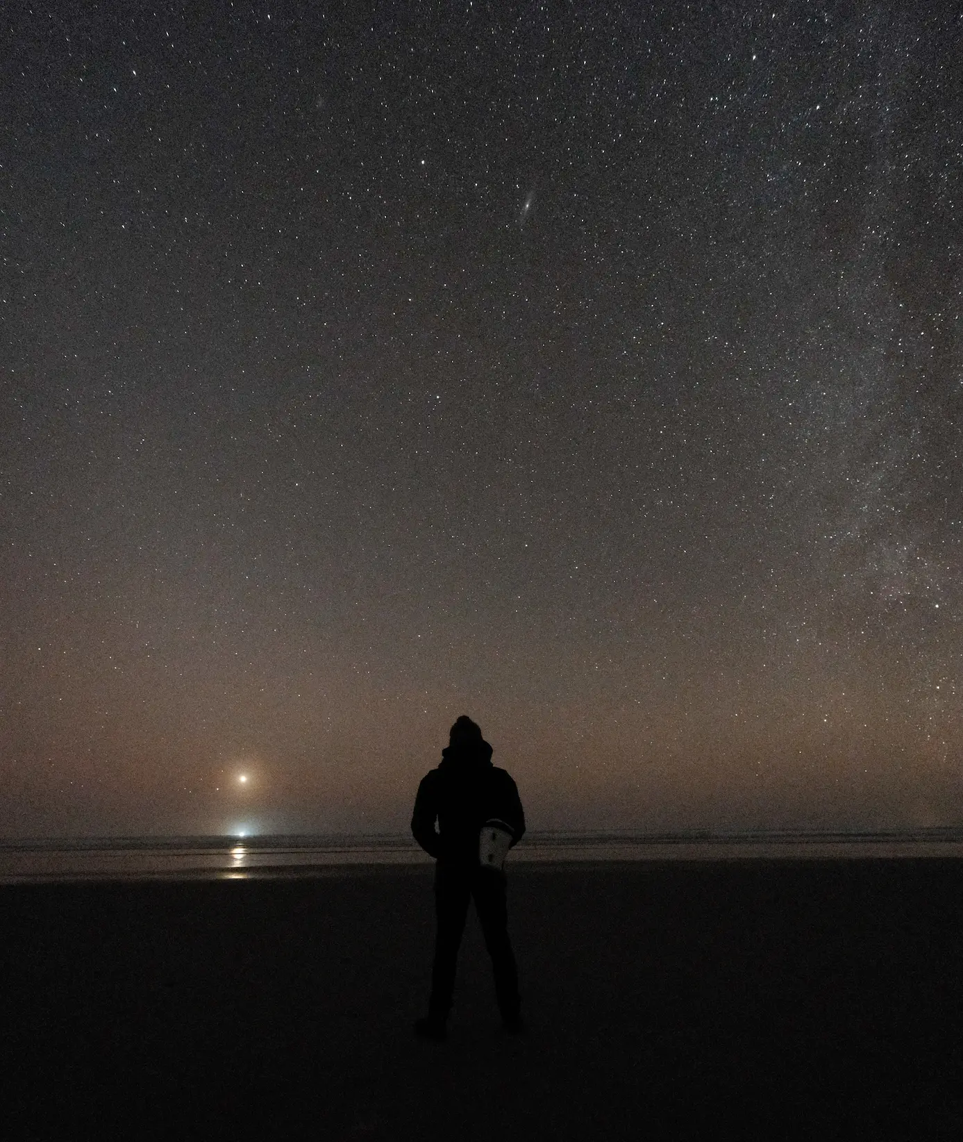 Venus, the Milky Way on the horizon of the ocean with a person standing with their back to the viewer