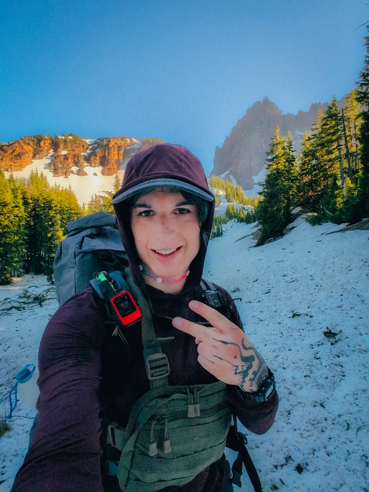 author looking at the camera holding a peace sign, smiling, with mountains behind her