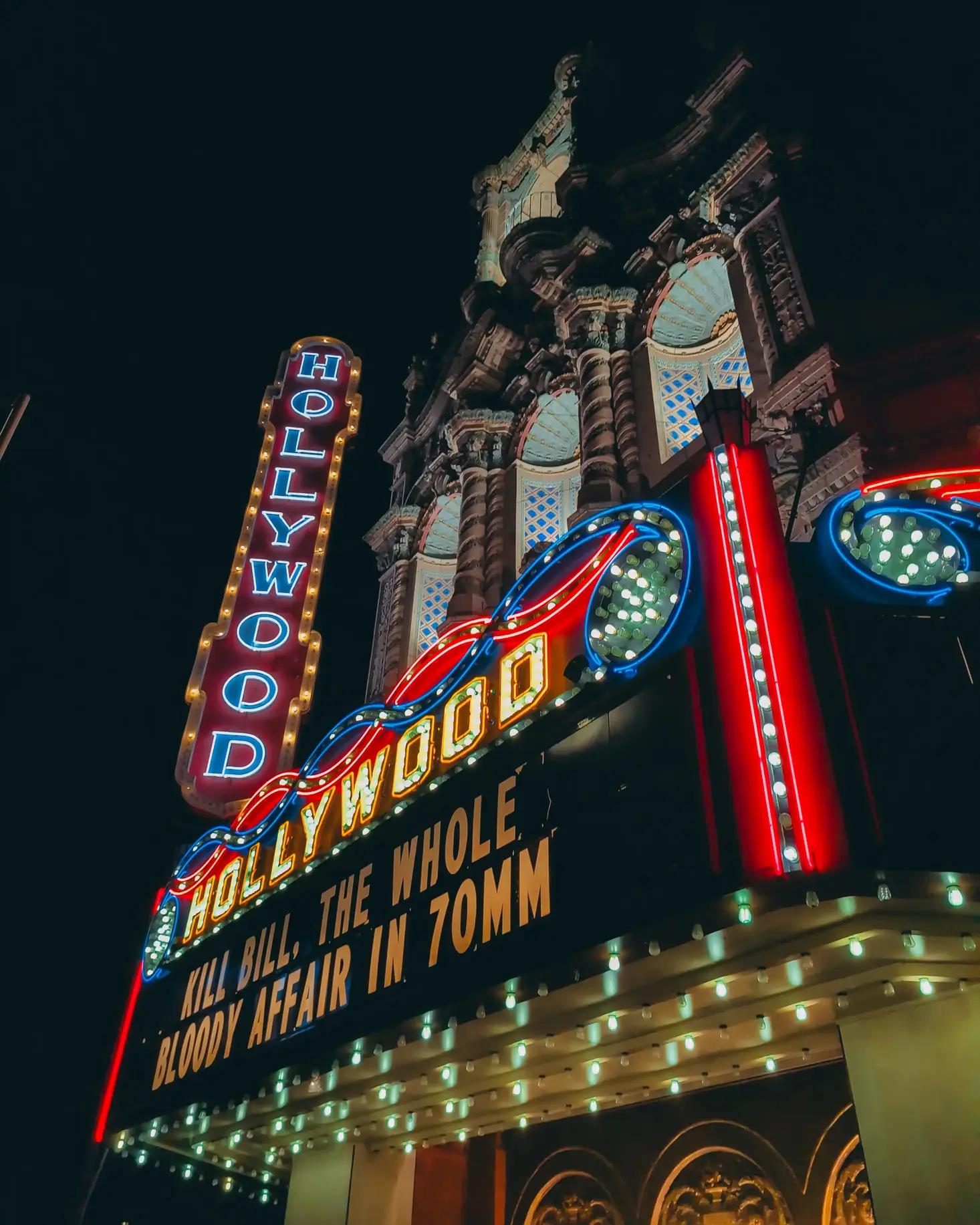 The Hollywood Theater in Portland, Oregon at night lit up with KILL BILL, THE WHOLE BLOODY AFFAIR IN 70MM on the marquee