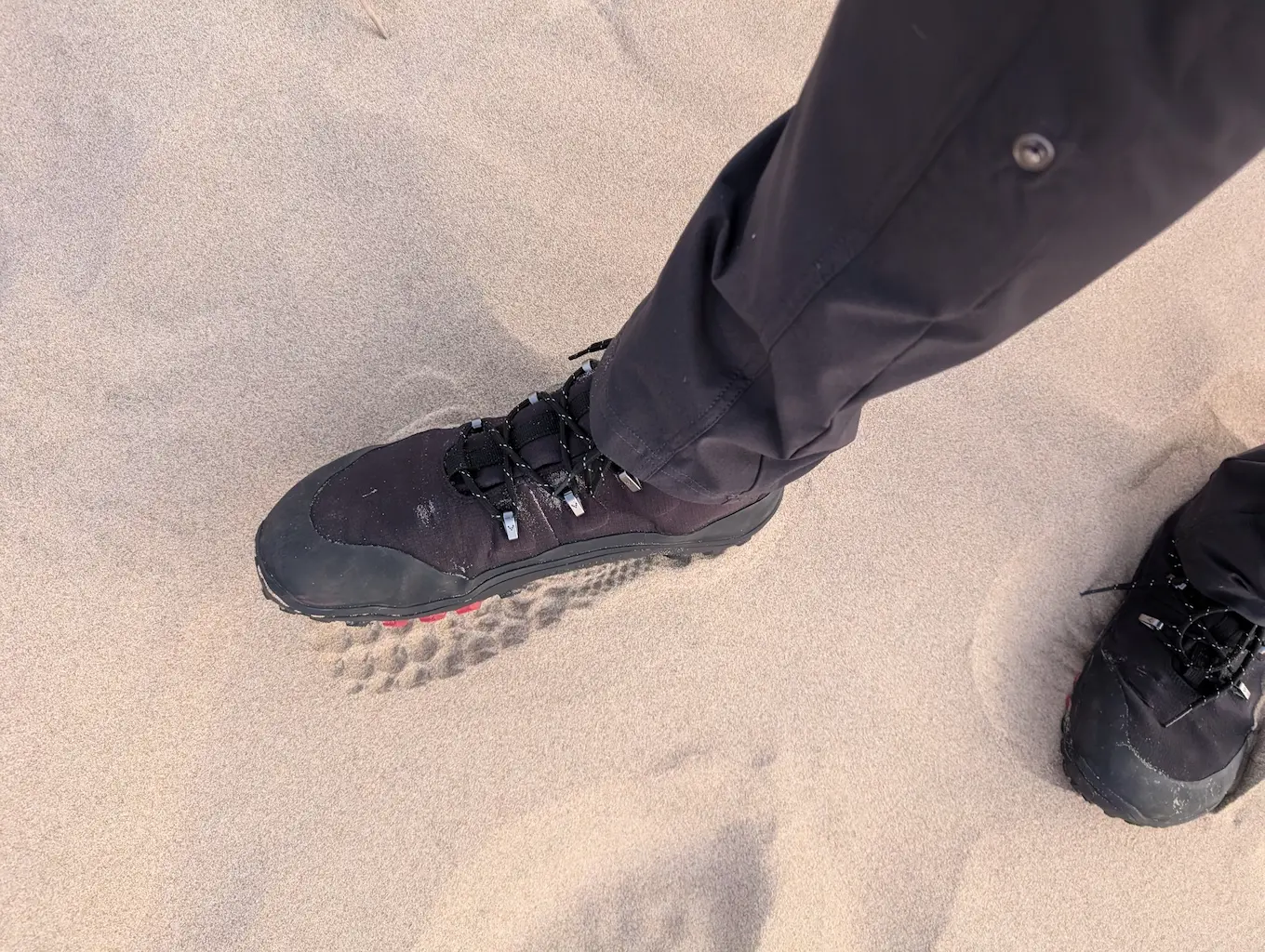 photo of footprints and the sand and the persons boots