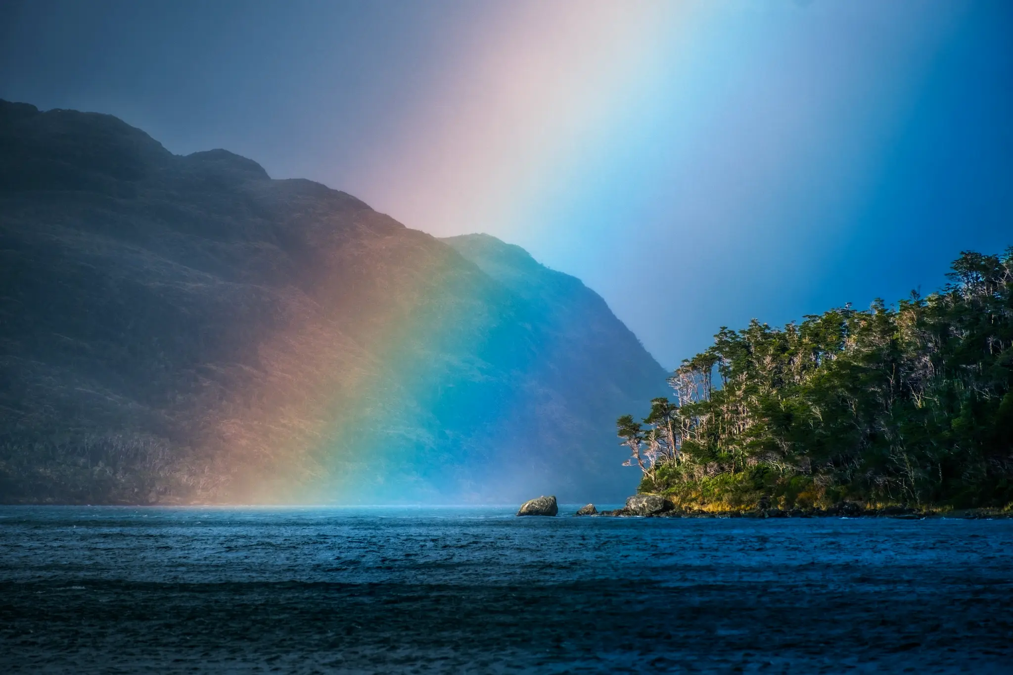 rainbow over water with an island on the right