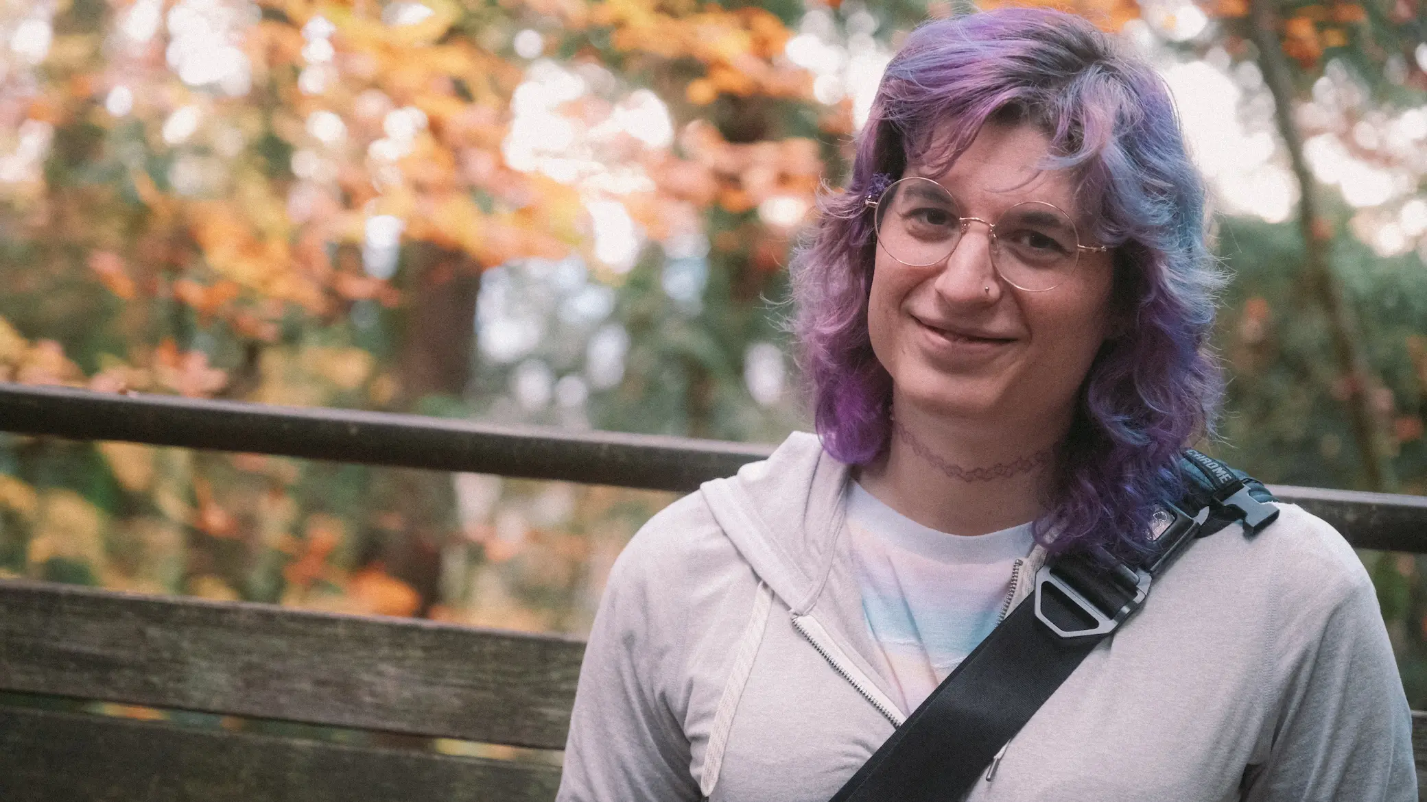 photo of the author with a soft smile with fall leaves behind her