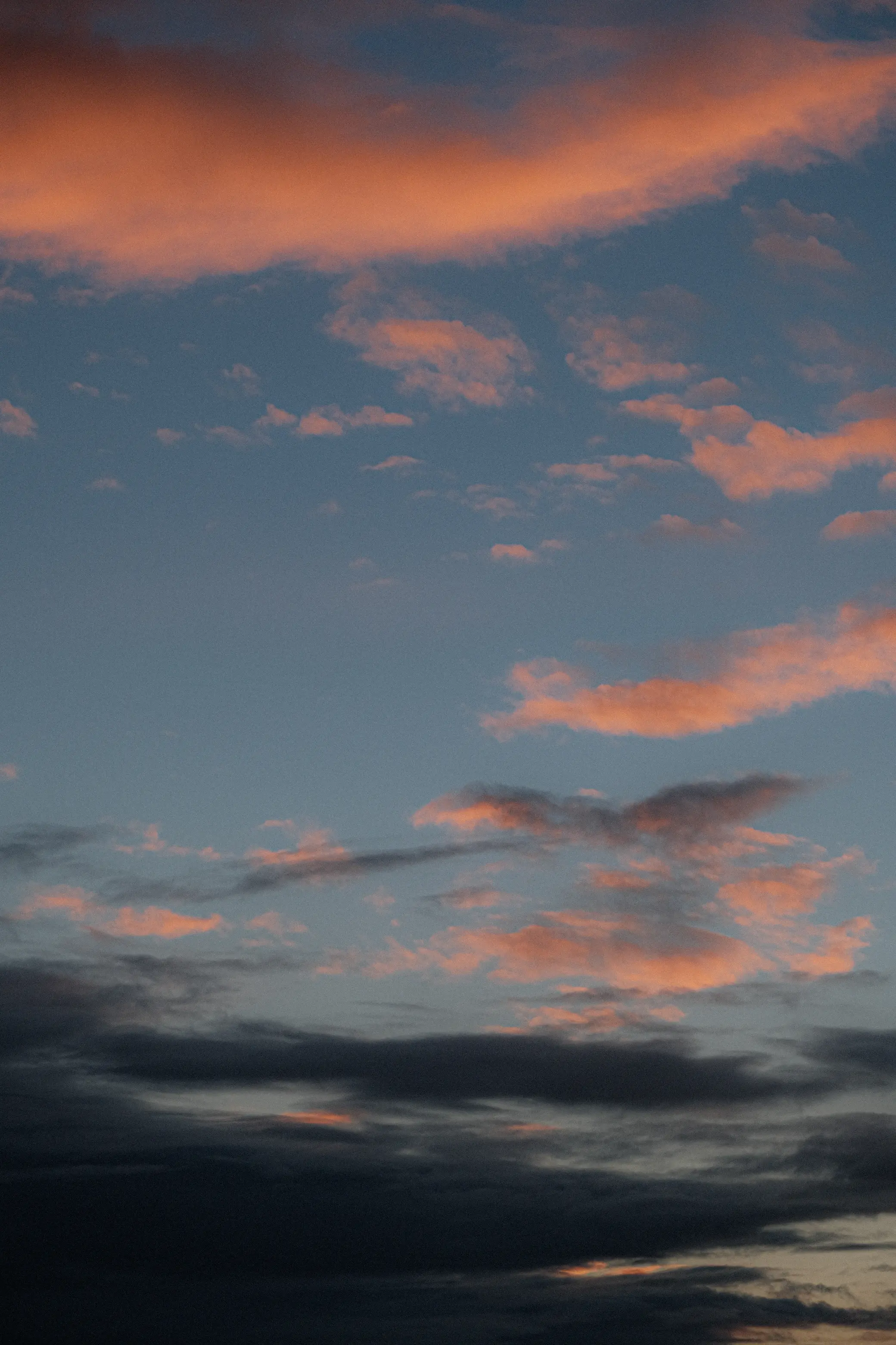 an orange sunrise in the sky with clouds and blue parts of the sky